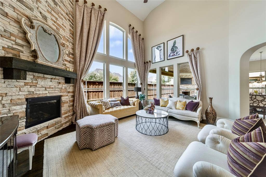 13018 Seattle Slew Street, Frisco, TX 75035 Two-story 20ft ceiling, stone-clad fireplace with wood mantel, arched entryways, large transom windows, and light-toned walls