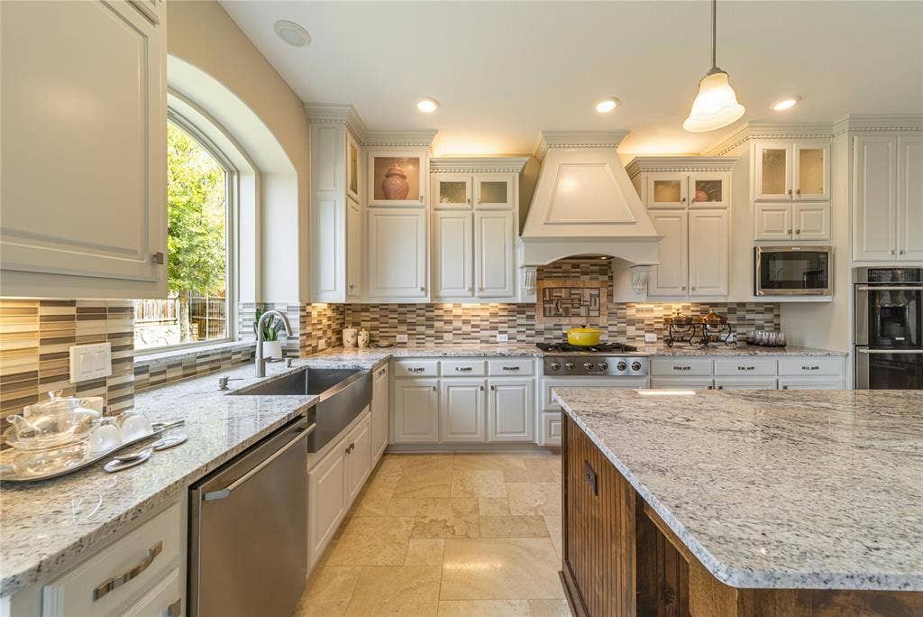 13018 Seattle Slew Street, Frisco, TX 75035 Spacious kitchen featuring white cabinetry, Travertine floor, Electrolux appliances, a large center island