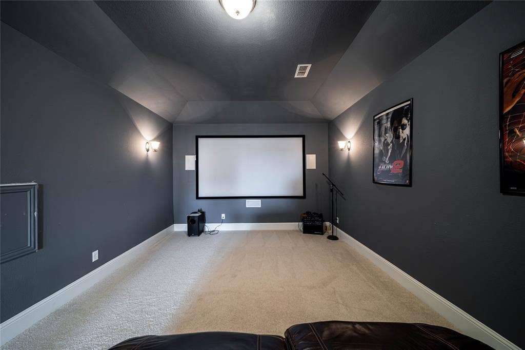 13018 Seattle Slew Street, Frisco, TX 75035 Dedicated media room featuring a projection screen, built-in wall speakers, and wall sconce lighting