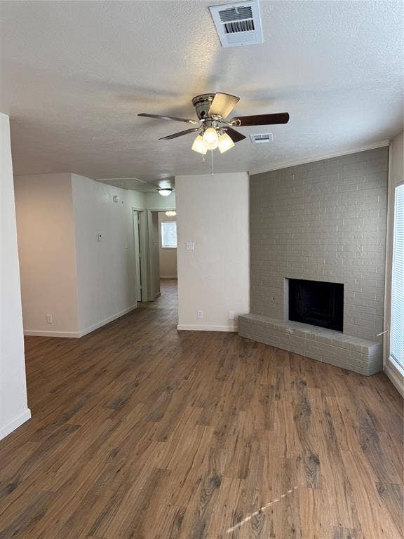 1104-1106 Mulkey Lane, Denton, TX 76209 Wood-finish flooring throughout, brick-surround fireplace with hearth, ceiling fan with integrated lighting, and white walls