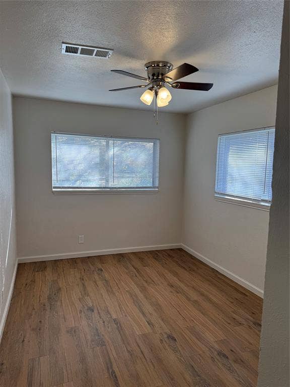 1104-1106 Mulkey Lane, Denton, TX 76209 Wood-finish flooring, white walls, two windows with blinds, and a ceiling fan with integrated lighting