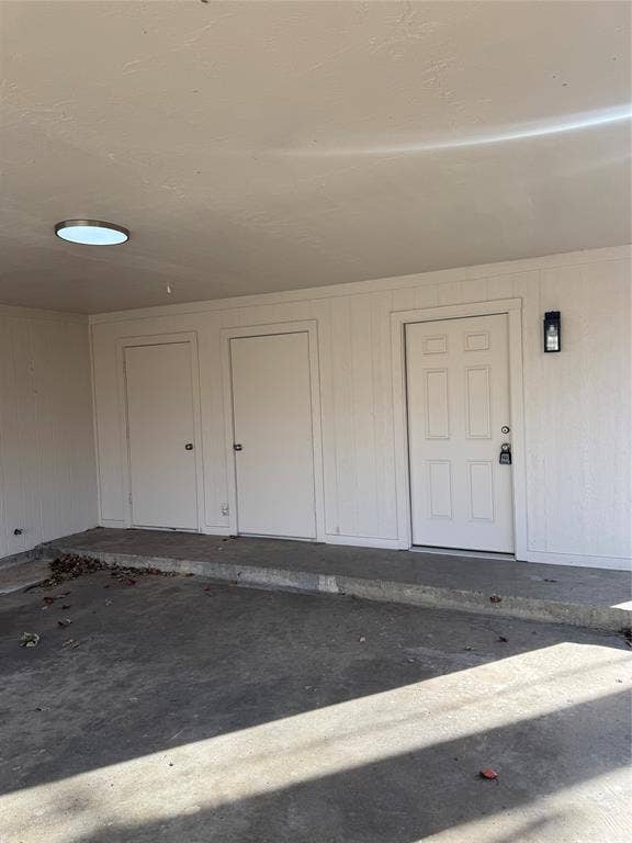 1104-1106 Mulkey Lane, Denton, TX 76209 Covered concrete patio area featuring multiple storage doors, a paneled entry door, and a flush-mount overhead light