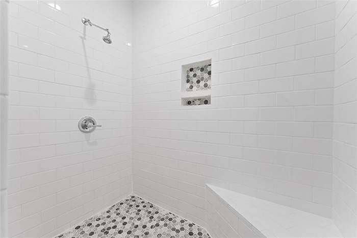 2405 Monroe Street, Commerce, TX 75428 Walk-in shower with white subway tile, mosaic tile flooring, shower niche, built-in bench, and polished chrome fixtures