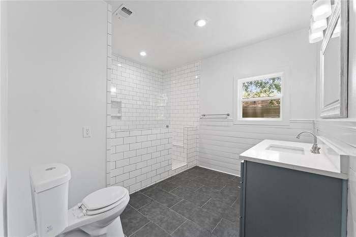 2405 Monroe Street, Commerce, TX 75428 Walk-in shower with subway tile surround, built-in shelving, and glass enclosure