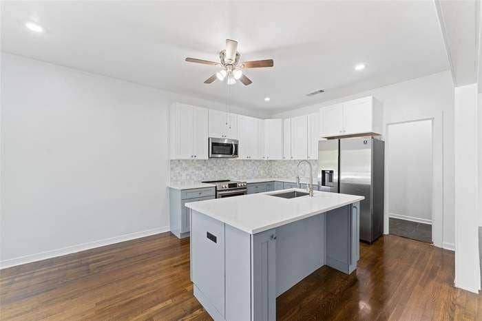 2405 Monroe Street, Commerce, TX 75428 Modern kitchen featuring a central island with a sink, white countertop, and gray cabinetry
