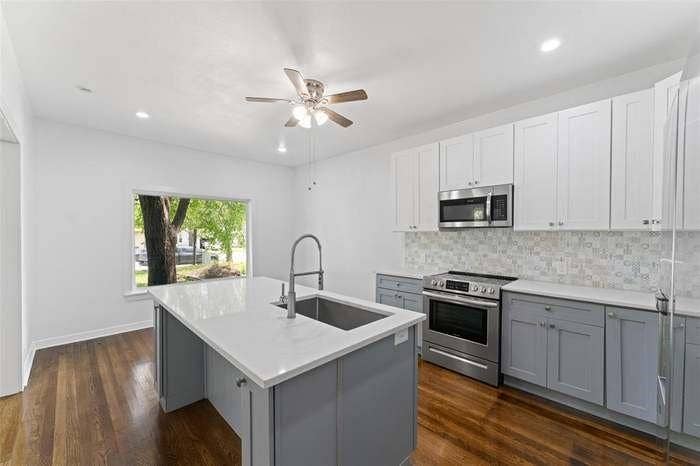 2405 Monroe Street, Commerce, TX 75428 Stainless steel appliances, wood-finish flooring, two-tone cabinetry, a ceiling fan, and recessed lighting