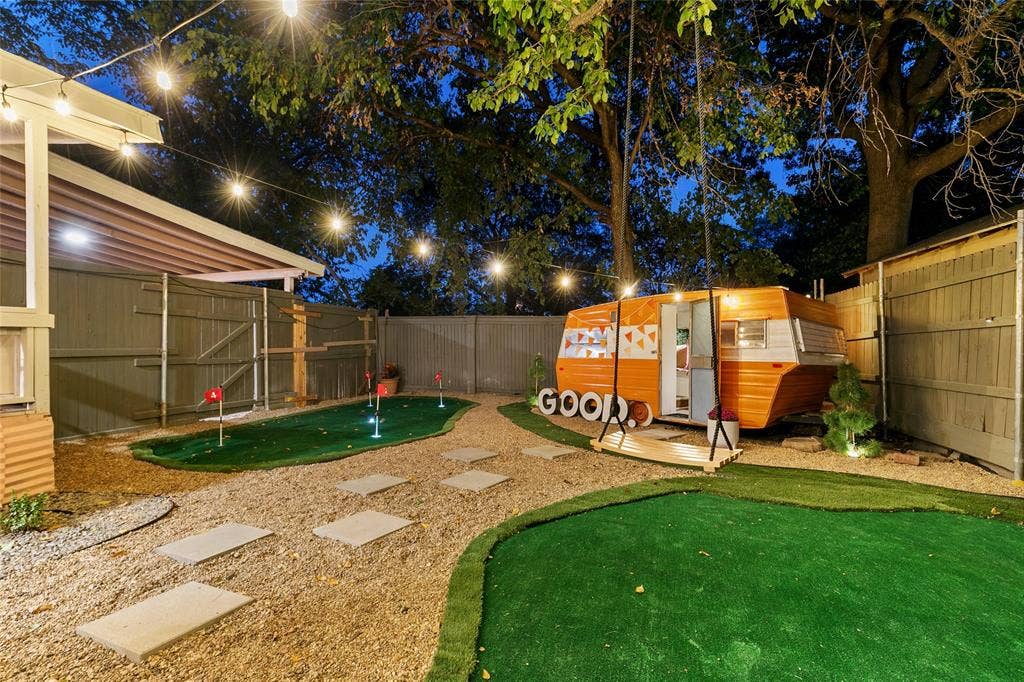 214 Short Street, McKinney, TX 75069 Putting green, gravel pathways with paver steps, string lighting, wood fencing, and a built-in swing