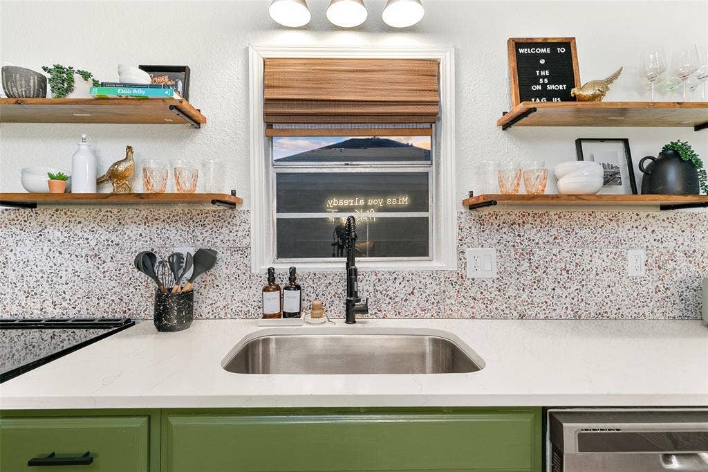 214 Short Street, McKinney, TX 75069 Stainless steel sink with a matte black faucet, light countertop, and green cabinetry
