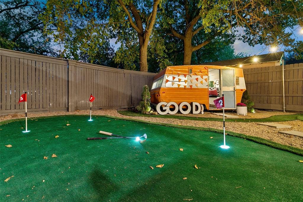 214 Short Street, McKinney, TX 75069 Backyard putting green with multiple holes, gravel pathways, a privacy fence, and a unique wood-sided structure