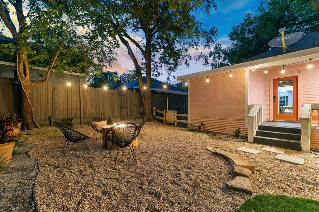 214 Short Street, McKinney, TX 75069 Gravel backyard with a built-in fire pit, string lighting, and wood privacy fencing