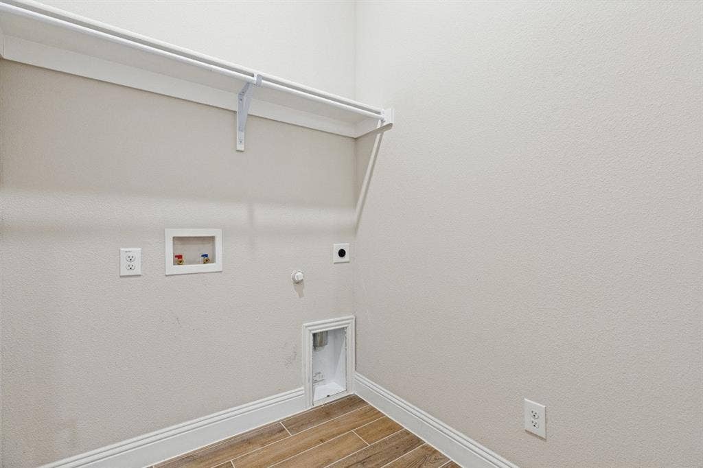 Laundry area featuring wood-look tile flooring, white shelving, and appliance hookups