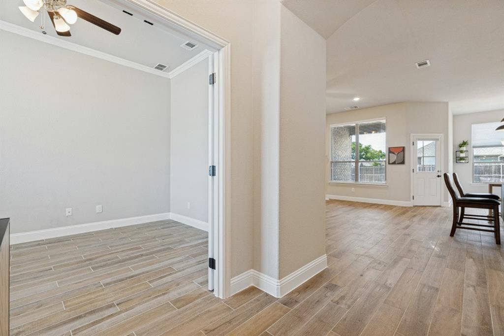 Wood-look tile flooring extending through main areas, recessed lighting, and crown molding