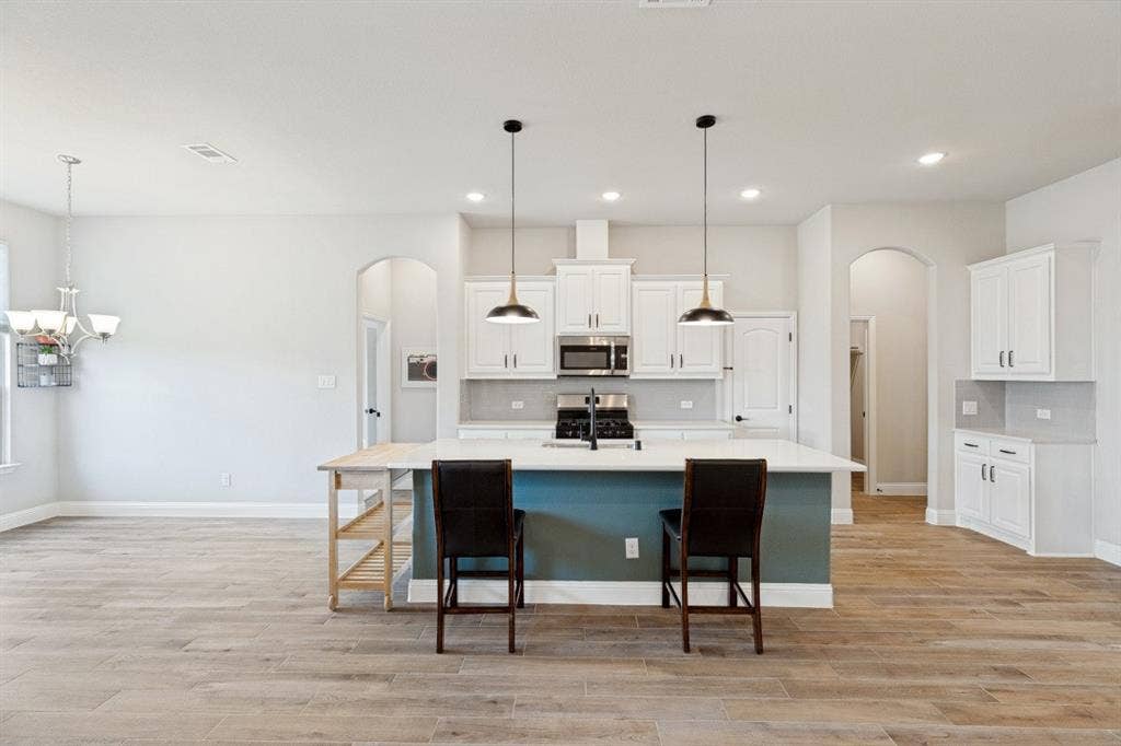 Stainless steel appliances with the exhaust hood that's vented to the exterior for cooking, quartz countertops, and the entire main area has the porcelain tile plank flooring easy to maintain and almost impossible to stain