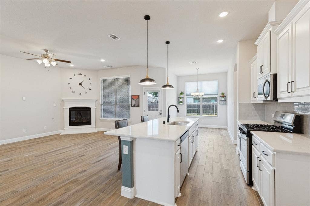 Gourmet kitchen with white cabinetry, stainless steel appliances, and a central island with a sink