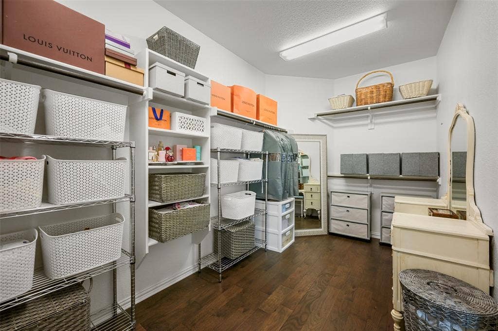 Walk-in closet featuring wood-finish flooring, built-in shelving, and a full-length mirror