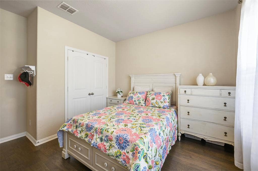 Wood-finish flooring with white trim, vaulted ceiling, and double-door closet