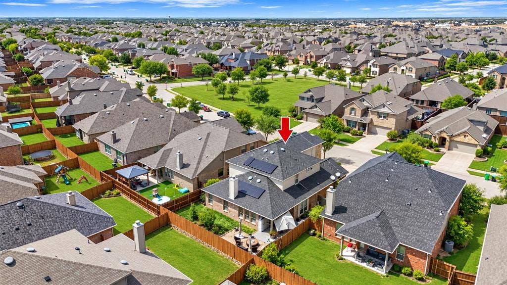 Property with solar panels, a fenced backyard, and an outdoor patio, situated in a residential neighborhood with green spaces and mature trees