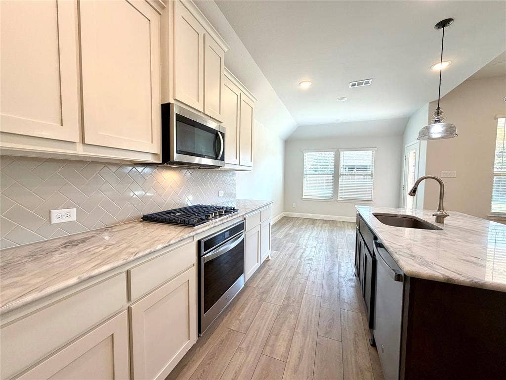 3806 Chicory Court, Melissa, TX 75454 This bright and airy kitchen is designed with an open-concept layout, featuring expansive quartz counter space that is perfect for meal preparation, stainless steel appliances, and a seamless, natural flow into the dining area, making it an ideal space for both daily living and hosting dinner gatherings.