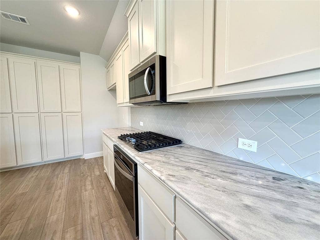 3806 Chicory Court, Melissa, TX 75454 This gourmet kitchen features a high-performance gas cooktop perfect for precision cooking, complemented by a convenient separate oven below for efficient meal preparation. The area includes a sleek, over-the-range vented microwave for optimal ventilation and offers an abundance of sprawling counter space, making it an ideal environment for both culinary enthusiasts and daily entertaining.