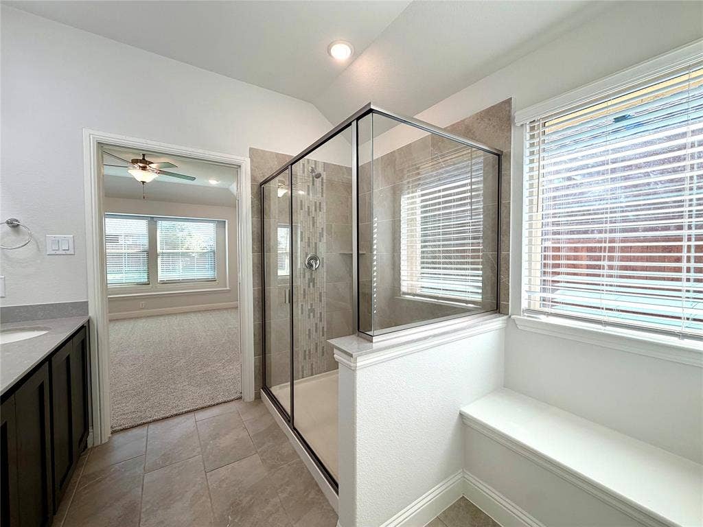 3806 Chicory Court, Melissa, TX 75454 This stunning primary bathroom features a spacious walk-in shower enhanced by a sleek glass enclosure, exquisite custom tile work, and a convenient, beautifully integrated built-in bench for added comfort and functionality.