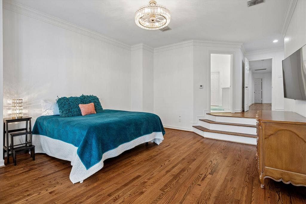 Hardwood flooring, crown molding, tiered steps, recessed lighting, and a crystal chandelier