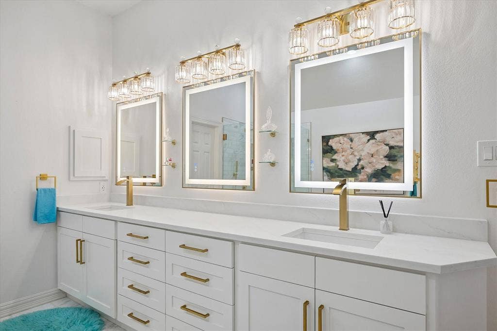 Dual vanities with white cabinetry, gold-finish hardware, and integrated sinks
