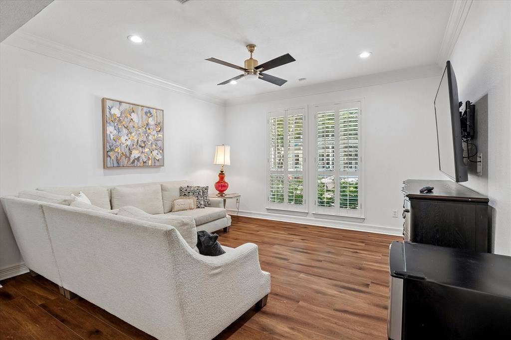 Wood-finish flooring throughout, crown molding, recessed lighting, ceiling fan with light, and plantation shutters