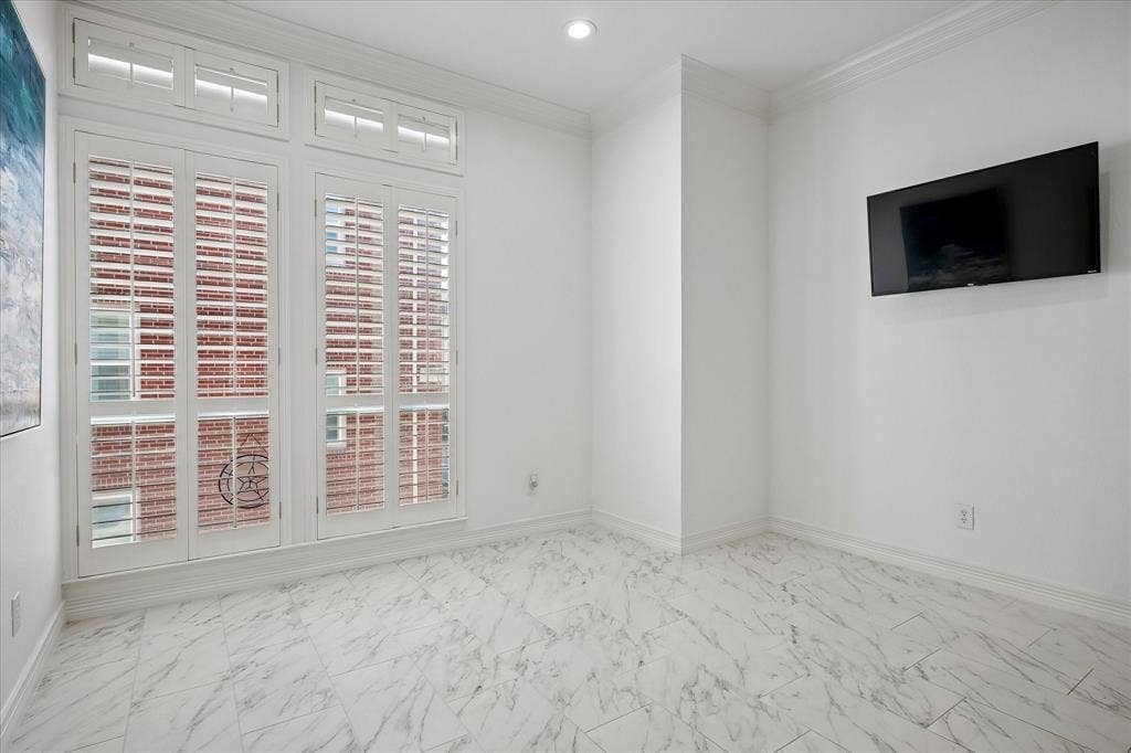 White tile flooring, extensive crown molding, recessed lighting, and large windows with plantation shutters