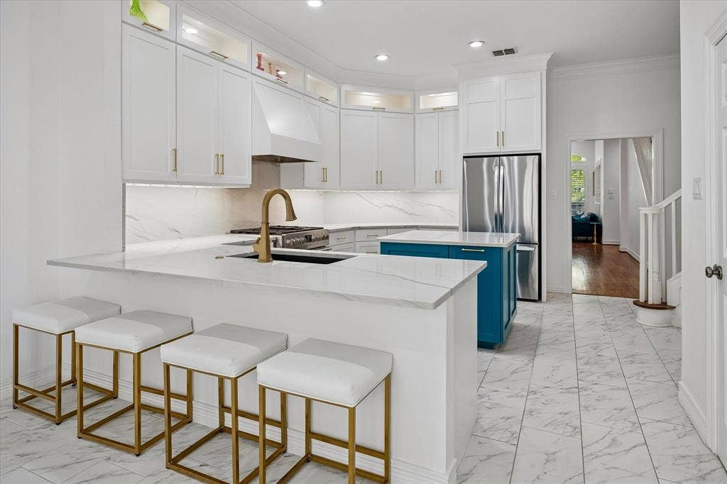 Kitchen featuring white cabinetry, a central island with a contrasting base, a built-in stainless steel refrigerator, stone countertops, and tile flooring