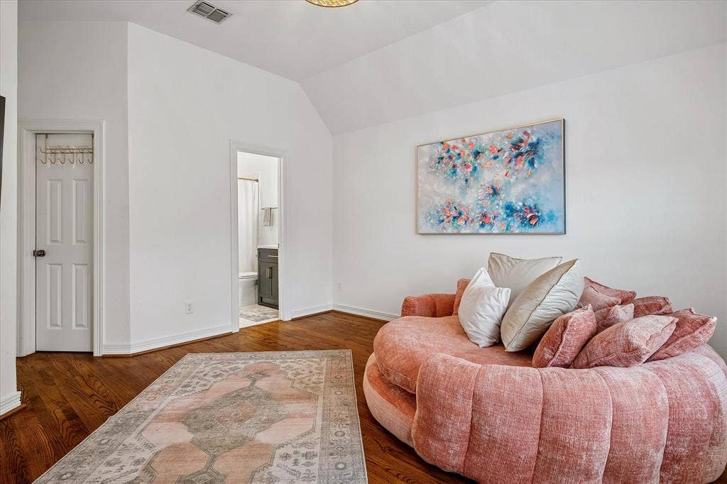 Vaulted ceiling, rich wood-finish flooring, white trim, and white walls