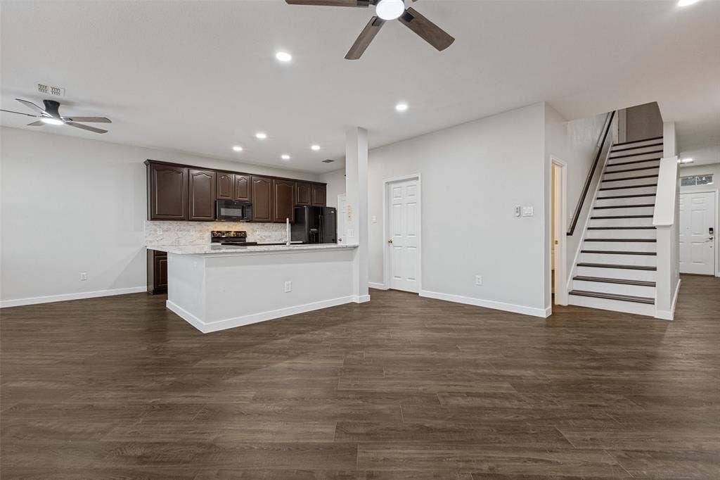 4215 Maidstone Drive, Garland, TX 75043 Wood-finish flooring throughout, dark wood cabinetry, white countertops, and a staircase with dark treads and white risers