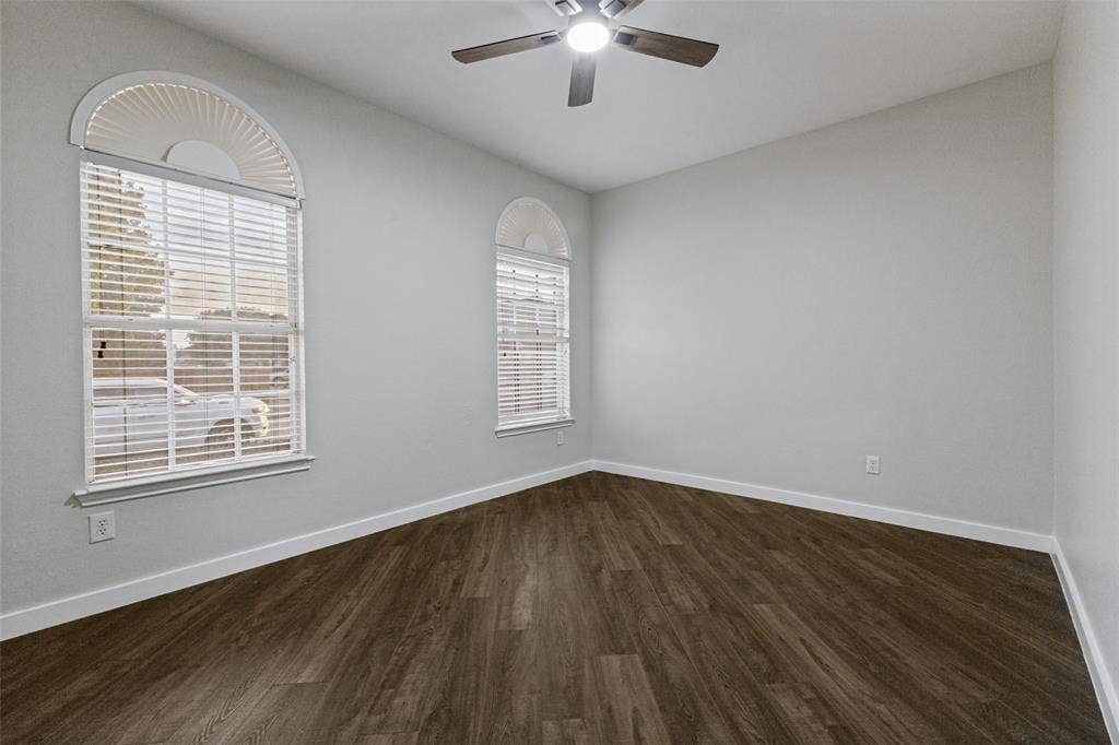 4215 Maidstone Drive, Garland, TX 75043 Wood-finish flooring, two large windows with arched transoms, and a ceiling fan with integrated lighting