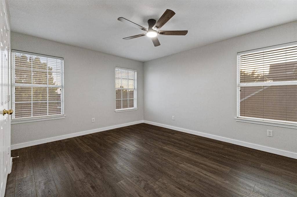 4215 Maidstone Drive, Garland, TX 75043 Hard-surface wood-finish flooring, white walls, three windows with blinds, and a ceiling fan with integrated lighting