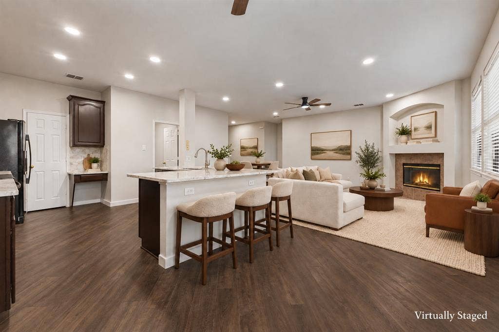 4215 Maidstone Drive, Garland, TX 75043 Open-concept living area featuring wood-finish flooring, a kitchen island with seating, a built-in fireplace, and recessed lighting.