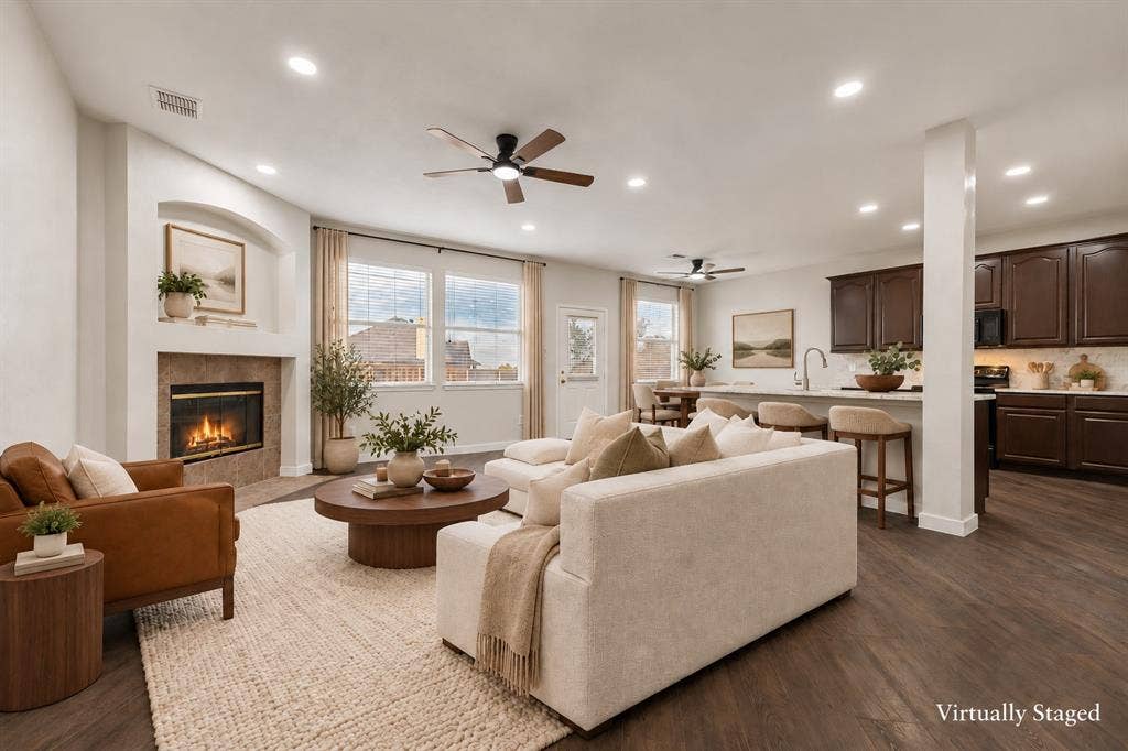 4215 Maidstone Drive, Garland, TX 75043 Spacious living area featuring wood-finish flooring, a tiled fireplace with an arched niche, recessed lighting, and ceiling fans