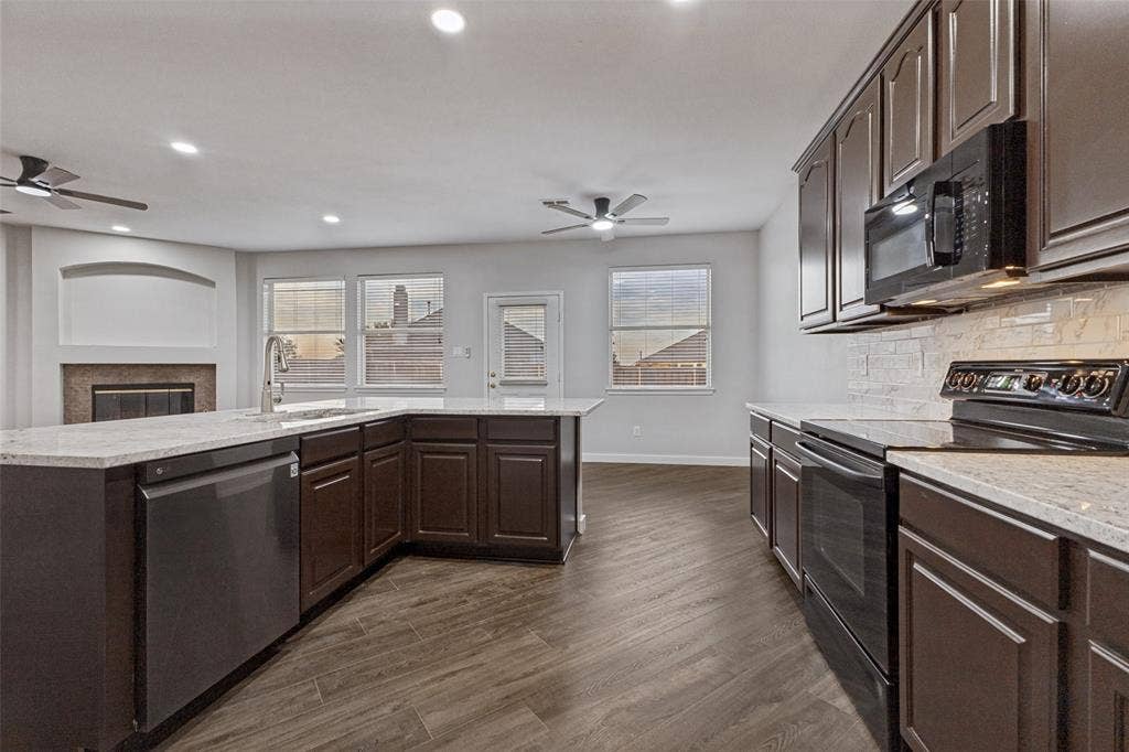 4215 Maidstone Drive, Garland, TX 75043 Kitchen featuring dark wood cabinetry, light-toned countertops, integrated stainless steel dishwasher, and black appliances