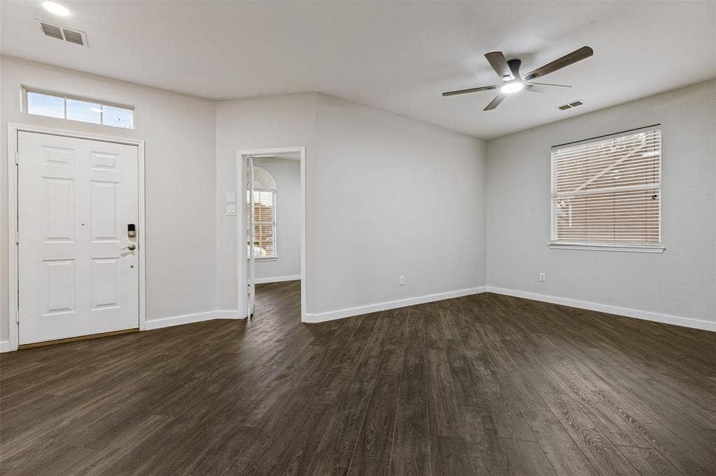 4215 Maidstone Drive, Garland, TX 75043 Wood-finish flooring, white paneled door with transom window, ceiling fan with integrated lighting, and multiple windows with blinds