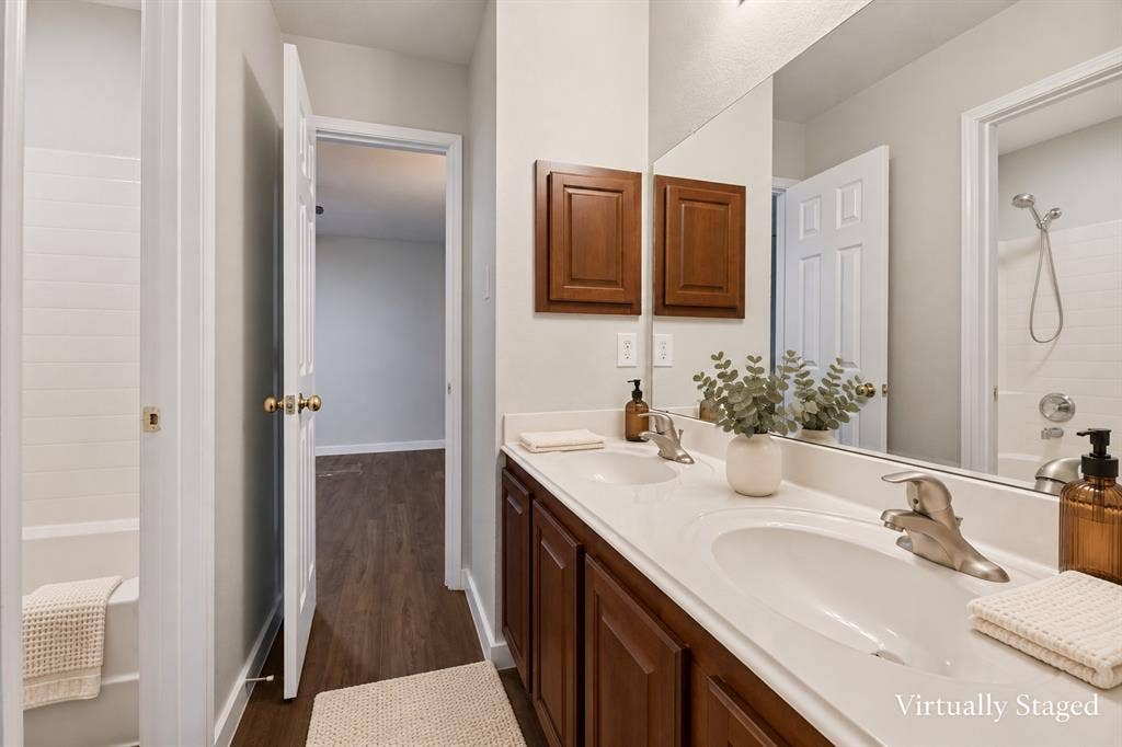 4215 Maidstone Drive, Garland, TX 75043 Dual vanity with integrated sinks and brushed nickel faucets, wood-finish cabinetry, and a full-width mirror