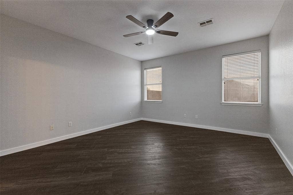 4215 Maidstone Drive, Garland, TX 75043 Primary bedroom with a ceiling fan with integrated lighting, wood-finish flooring, multiple windows with blinds.