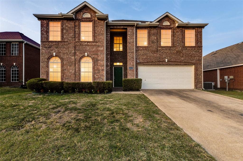 4215 Maidstone Drive, Garland, TX 75043 Brick exterior construction, prominent arched windows, attached garage, concrete driveway, and front landscaping