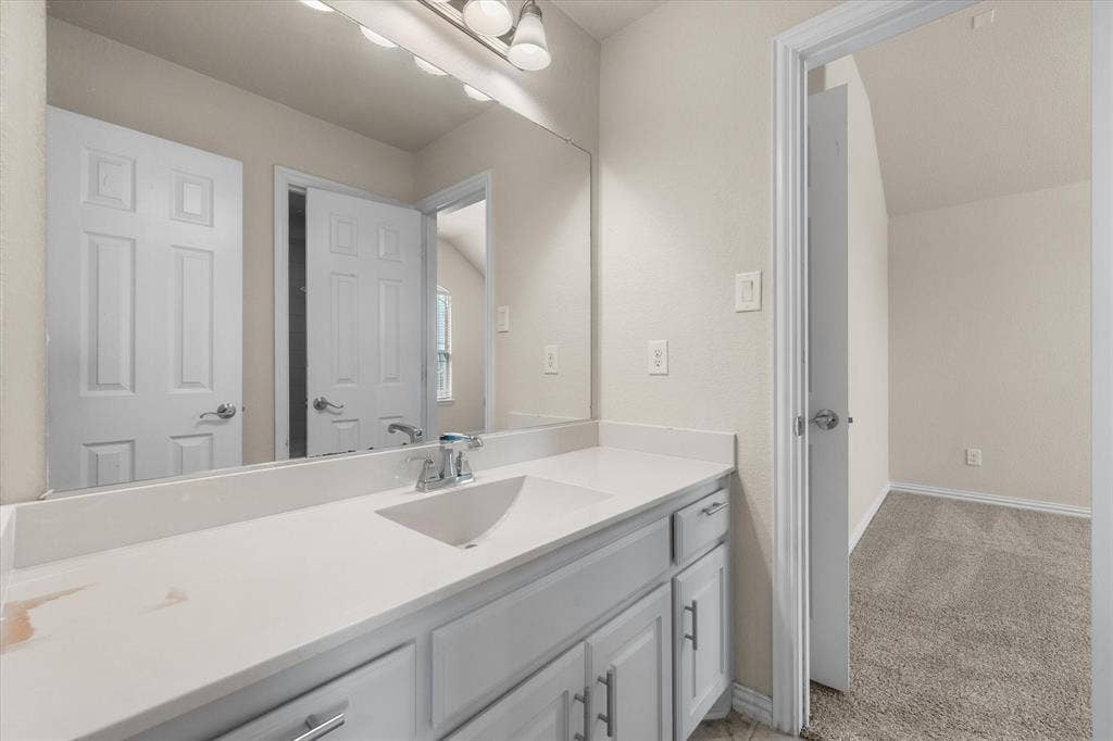 White vanity with chrome hardware, an integrated sink, and a large wall-mounted mirror