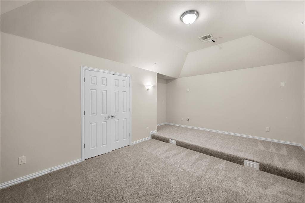 Carpeted room with a stepped floor, double panel doors, and neutral wall paint