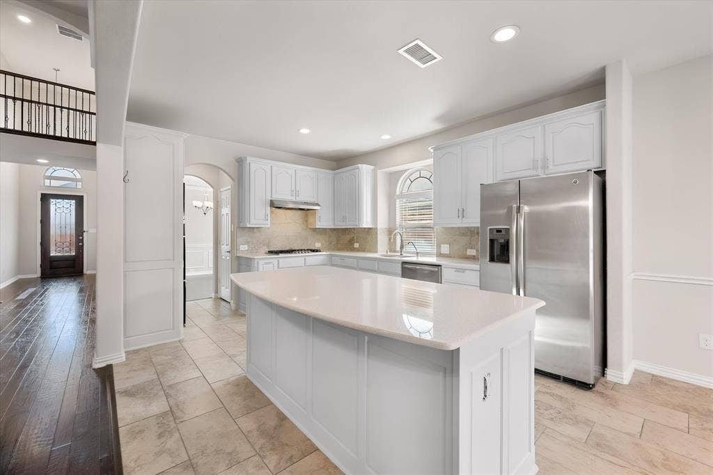 Kitchen featuring white cabinetry, stone countertops, stainless steel appliances, and a central island