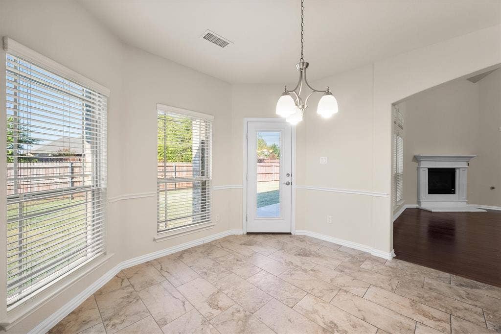 Tile flooring, bay windows, glass-paneled door, chandelier, and a decorative fireplace