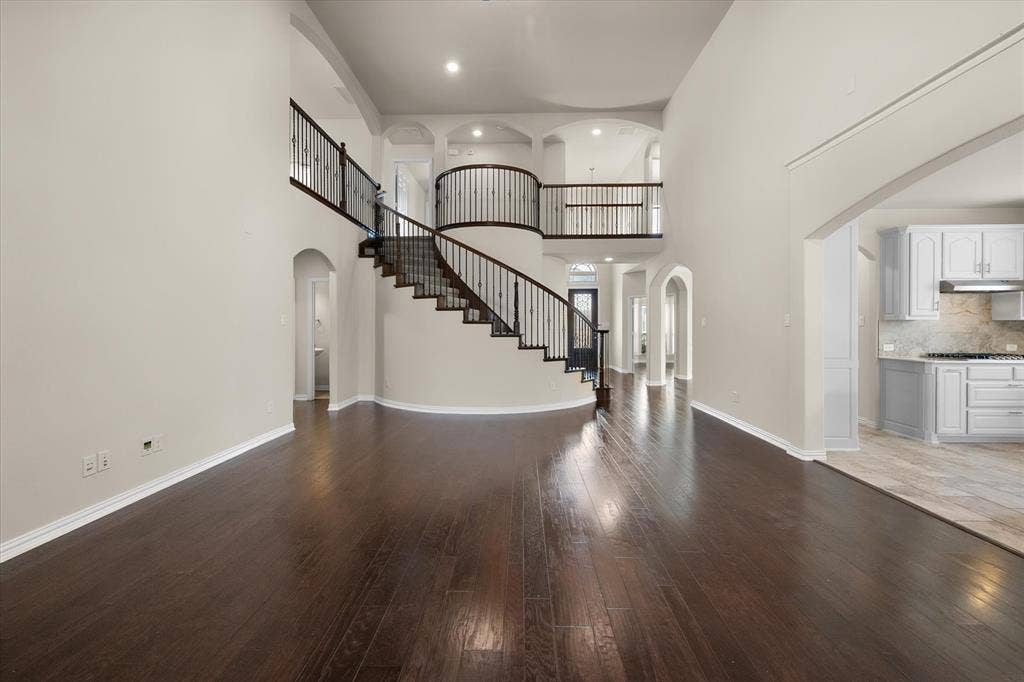 Expansive living area with wood-finish flooring, high ceilings, and recessed lighting