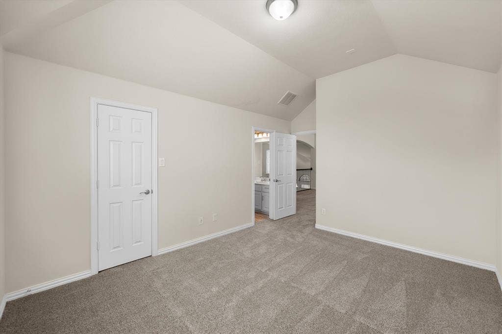 Vaulted ceiling, neutral wall paint, gray carpet flooring, white paneled door, flush mount ceiling light