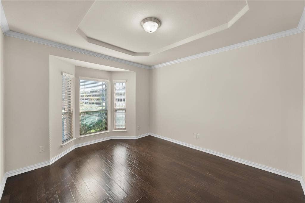 Recessed ceiling with layered trim, wood-finish flooring, and bay windows