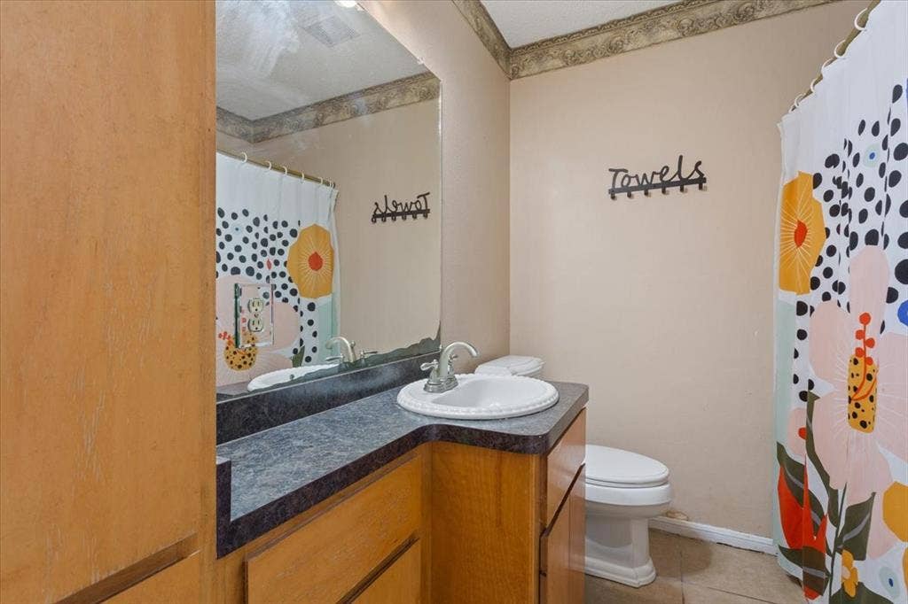 Vanity with integrated sink, dark countertop, and wood-finish cabinetry