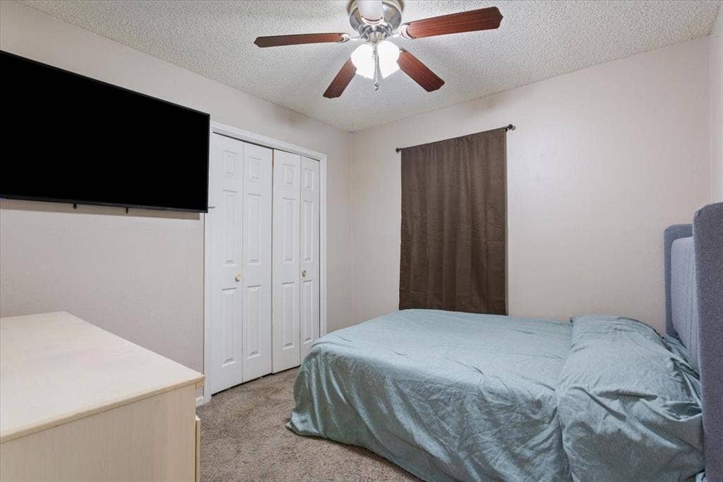 Ceiling fan with wood-finish blades, bi-fold closet doors, wall-to-wall carpeting