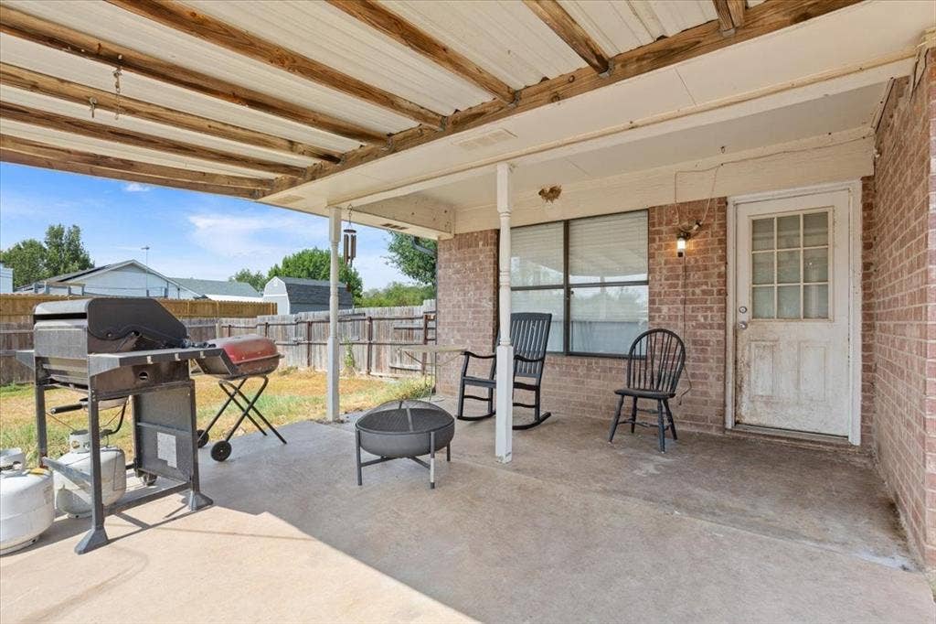 Covered patio with a concrete surface, brick exterior, and wood-paneled ceiling